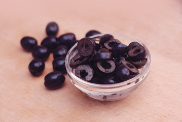 Marinated slices black olives in bowl isolated on wooden background