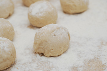 Fototapeta na wymiar Dough balls made for cooking pastries with flour on the table
