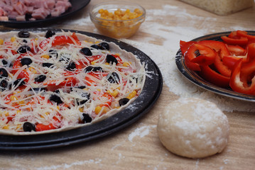 Prepared Italian pizza with sauce, cheese and other ingredients other on the wooden background