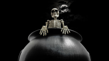 Halloween skeleton standing inside cauldron under a nice moon covered with dark clouds.