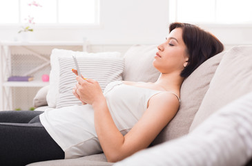 Young woman using a mobile phone on sofa.