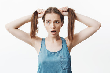 Fototapeta premium Close up isolated portrait of funny charming caucasian student girl with dark long hair mowing eyes with opened mouth, having fun, trying make sister laugh.