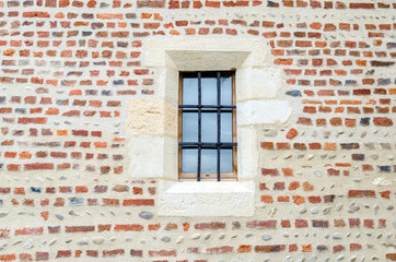 Fototapeta na wymiar little medieval window in the middle of a brick wall of a little church