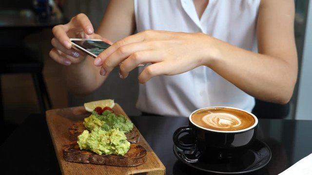 Woman Hands Taking Picture Of Coffee And Avocado Toast With Smartphone. Closeup. 4K.  