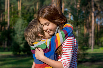 The sister hugs her little brother.