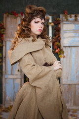 Medieval outfit of a princess, a sorceress, a witch with a hood and a tiara on her head. Beautiful girl teenager, women. Portrait, hands cross on cross, cross arms.