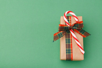 Christmas gift box in craft wrapping paper on green background