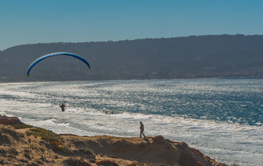 Fototapeta premium Paragliding over the beach and sea in Monterey Ca.