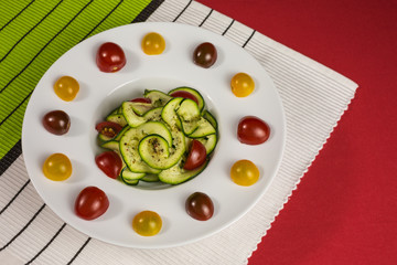 spiralized  vegetarian zucchini noodles with  yellow, red and dark red tomatoes