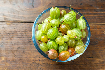 Gooseberries in a plate on a wooden background