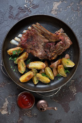 Above view of roasted lamb meat served with potato wedges in a frying pan, vertical shot