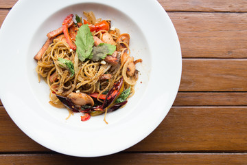 Dried chili spaghetti on a white plate on the wooden table top view