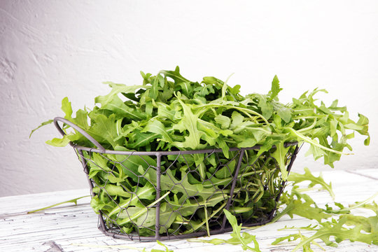 Fresh green arugula in basket on wooden table. Arugula is rich in vitamins and trace elements.