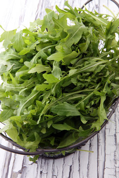 Fresh green arugula in basket on wooden table. Arugula is rich in vitamins and trace elements.