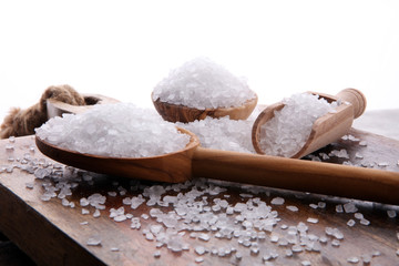 sea salt with wooden spoon and crystals of salt on wooden background.