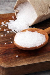 Fototapeta na wymiar sea salt with wooden spoon and crystals of salt on wooden background.