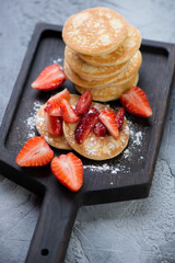 Close-up of pancakes served with strawberry and powdered sugar, selective focus, vertical shot