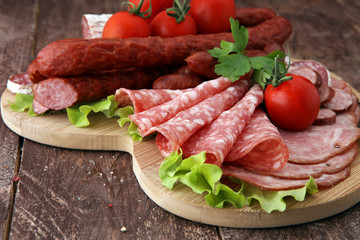 Food tray with delicious salami, pieces of sliced ham, sausage, tomatoes, salad and vegetable - Meat platter with selection - Cutting sausage and cured meat