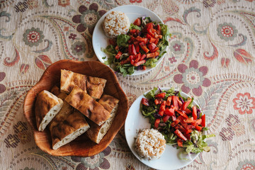 Top view breakfast for two, vegetable salad with rice and cake with sesame seeds on patterned tablecloth
