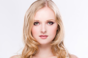 Portrait einer h&uuml;bschen blonden jungen Frau geradeaus schauend vor weissem Hintergrund