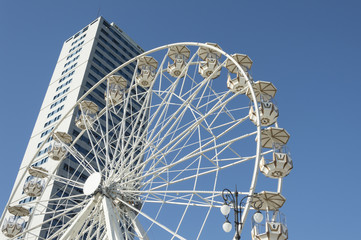 Fototapeta premium Panoramic ferris wheel with skyscraper on background