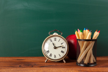 School supplies on a wooden table and blackboard background