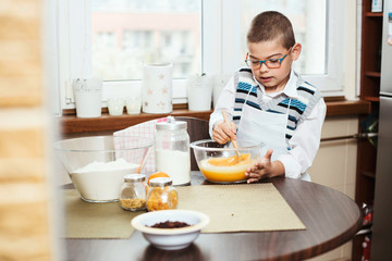7-year-old boy mixing ingredients for baking a Christmas cake. Lifestyle image of son helping in the kitchen.