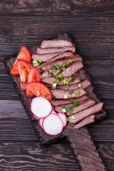 Grilled beef steak with spring onion on cutting board.