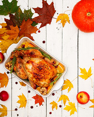 Roasted turkey garnished with cranberries on a rustic style table decorated with pumpkins, orange, apples and autumn leaf. Thanksgiving Day. Flat lay. Top view