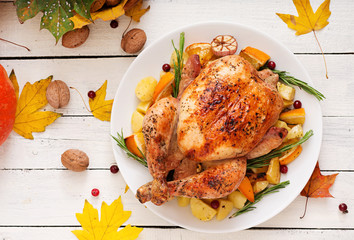 Roasted turkey garnished with cranberries on a rustic style table decorated with pumpkins, orange,...