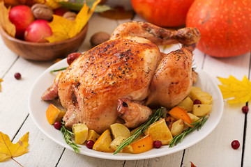 Roasted turkey garnished with cranberries on a rustic style table decorated with pumpkins, orange, apples and autumn leaf. Thanksgiving Day.