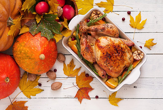 Roasted turkey garnished with cranberries on a rustic style table decorated with pumpkins, orange, apples and autumn leaf. Thanksgiving Day. Flat lay. Top view