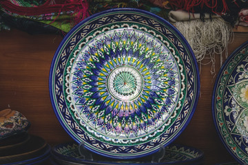 Fototapeta na wymiar Ethnic Uzbek ceramic tableware. Decorative ceramic plate with traditional uzbekistan ornament.