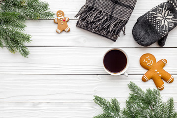 Christmas evening. Gingerbread man and knitten mittens near spruce branch on white wooden background top view copyspace © 9dreamstudio