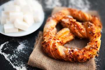 Unhealthy food concept - sugar and fresh pastry on dark background. Sweet pretzels with powdered sugar, macro..