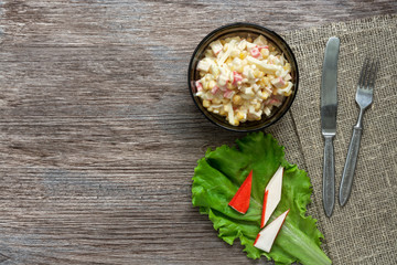 Salad of crab and corn on a wooden surface, top view.