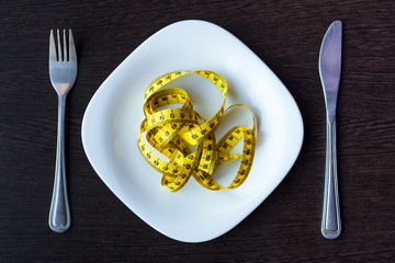diet, healthy eating, food and weigh loss concept - close up of green apple and measuring tape with salad on wooden table