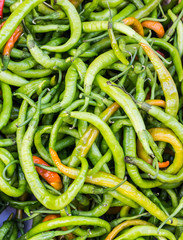 pile of green spicy hot chili peppers in a box on the market