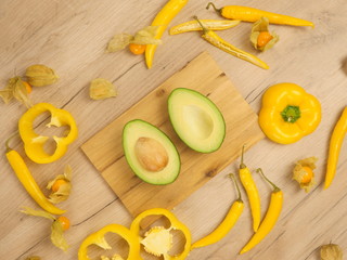 Organic food composition on the wooden table. Healthy vegetarian food on the white wooden background. Fresh and rape avocado, yellow paprika and chili peppers. Organic rape avocado in the kitchen.