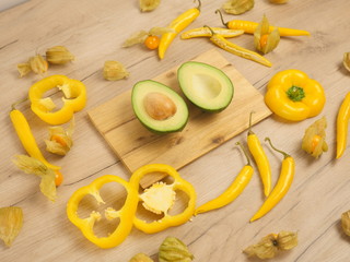 Organic food composition on the wooden table. Healthy vegetarian food on the white wooden background. Fresh and rape avocado, yellow paprika and chili peppers. Organic rape avocado in the kitchen.