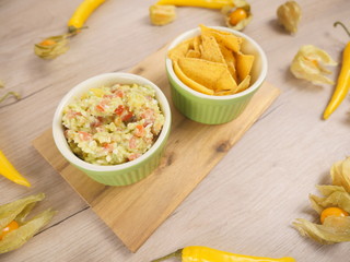 Guacamole from avocado delicious Mexican food. Guacamole with tortilla chips dish. Organic food composition on the wooden table. Healthy vegetarian food on the white wooden background. Healthy food.
