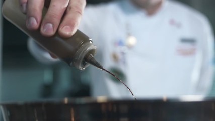 Chef adds olive oil to the dish, cooking in slow motion, falling liquid in 240 frames per second, cooking food - Powered by Adobe