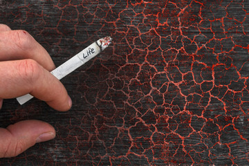 Young man holding a cigarette in hand. Concept of tobacco addiction and the danger of smoking....
