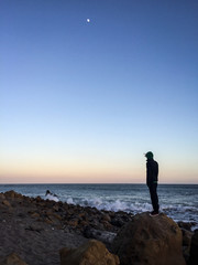 man standing on a rock at the ocean