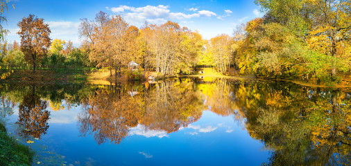 Sunny autumn landscape with blue sky over lake