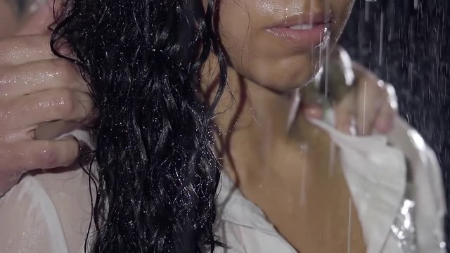 Close-up. Strong male hands caressing my woman in the dark on the street in the rain. Beautiful female lips.