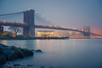Brooklyn bridge and Manhattan at foggy evening, New York City