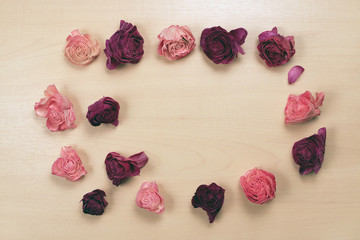 Wilted roses on pastel wooden background, top view