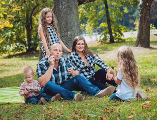 Fototapeta premium Young family with cheerful children in the park