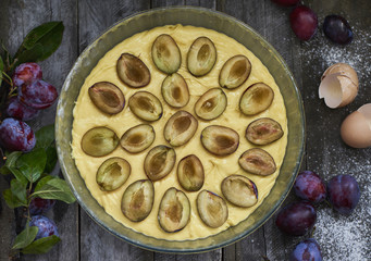 Homemade plum pie with fresh plums on wooden background